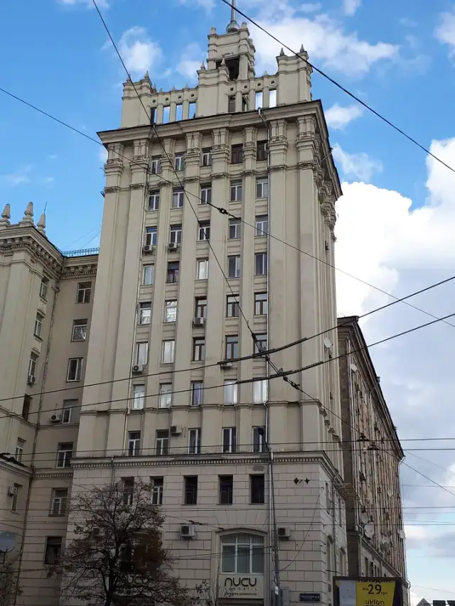 Висока світла башта будинку міськвиконкому на майдані Конституції з декоративним завершенням і тролейбусними дротами