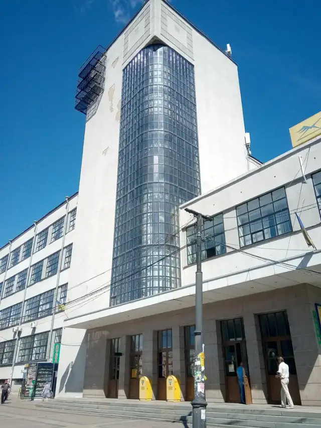Високий конструктивістський фасад харківського поштамту зі скляною вертикаллю, жовтими поштовими скриньками та прапорами