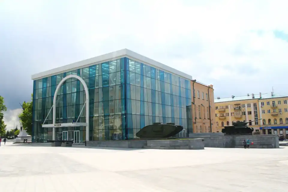 Скляний фасад Харківського історичного музею з білою аркою, входом із написом МУЗЕЙ та військовою технікою на відкритому майданчику