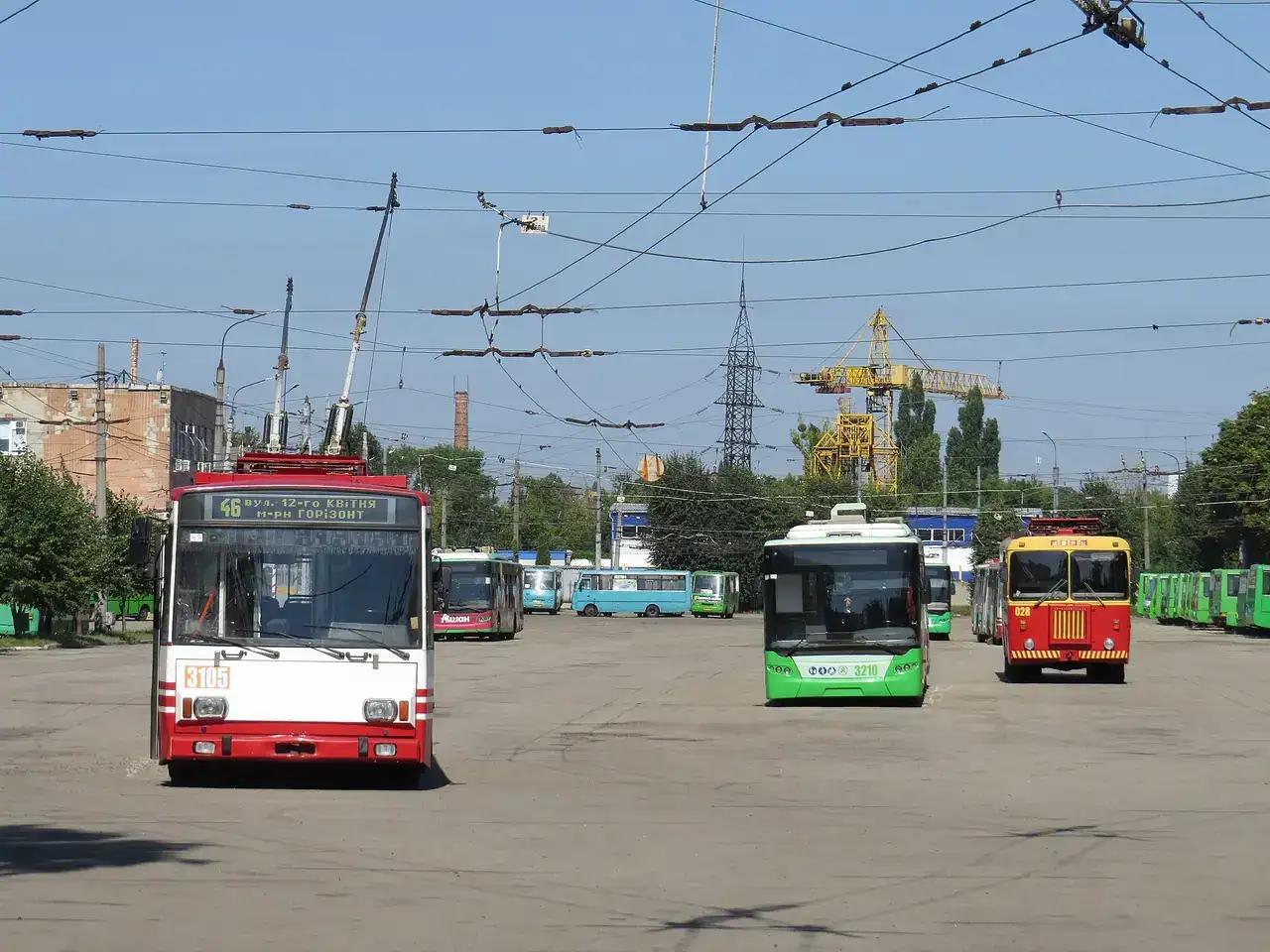 Тролейбуси різних моделей на відкритій території депо номер 3 під густою контактною мережею в ясний літній день